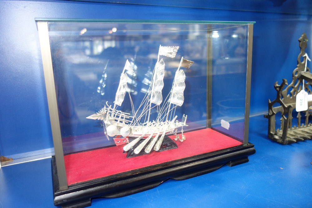 A CHINESE WHITE METAL SHIP in a glazed and ebonised case