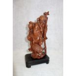 AN ORIENTAL CARVED WOODEN STUDY OF AN OLD MAN with a bird, 24 cm high (including stand)