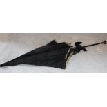 A VICTORIAN 'MOURNING' PARASOL, in black silk, with a silver handle