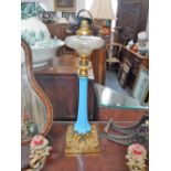 A VICTORIAN OIL LAMP with a blue glass column on an ormolu brass base, with a cut glass reservoir,