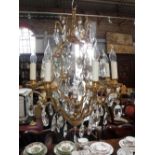 A LARGE BRASS EIGHT BRANCH CHANDELIER hung with many cut glass drops, 64 cm high and four matching