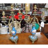 A PAIR OF CONTINENTAL BRASS CANDELABRA with blue and floral ceramic centres (drilled and converted