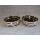 A PAIR OF SILVER WINE COASTERS with wooden bases