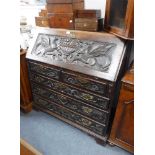 AN 18TH CENTURY OAK BUREAU with later carved decoration and the interior fitted with simulated