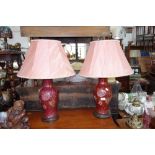 A PAIR OF TABLE LAMPS in the form of red glazed vases, with pink shades