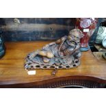 AN ASIAN CARVED HARDWOOD STUDY OF A MAN RECLINING, on a carved wooden base, 38 cm wide