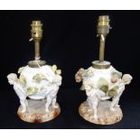 A PAIR OF CONTINENTAL CERAMIC OIL LAMPS supported by cherubs (with later electric fittings, not