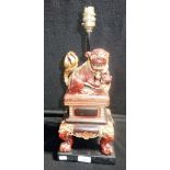 AN ORIENTAL TABLE LAMP, decorated with a red lacquered temple lion on a footed casket, 34.5cm