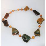 A GREEN AMBER NECKLACE with eight various shaped beads, interspersed with round beads, chain