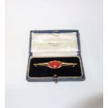 A CORAL AND GOLD BAR BROOCH, the oval shaped coral collet-set to the centre, the reverse engraved