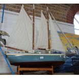 A 20TH CENTURY PAINTED SCRATCH BUILT MODEL of a two masted schooner, on pine dis