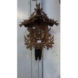 AN EARLY 20TH CENTURY CUCKOO CLOCK of traditional form, carved with Edelweiss and a stag's head