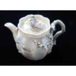 A JAPANESE MINIATURE TEAPOT with relief prunus decoration, the base with an impressed mark, Meiji