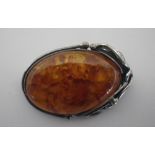 AN 'AMBER' OVAL BROOCH, set in a silver frame