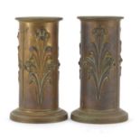 Pair of Aesthetic brass cylindrical Spill vases, each embossed with three panels of stylised