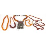 Four amber coloured bead necklaces and an agate necklace, one with a large silver coloured metal