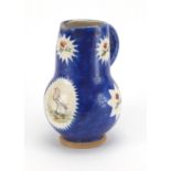 Middle Eastern blue ground pottery jug, hand painted with panels of flowers and a bird, 22cm