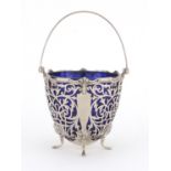 Silver four footed basket, with swing handle, pierced decoration and blue glass liner, indistinct