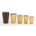 Graduated set of four 19th century horn travelling beakers with silver rims, housed in a tan leather