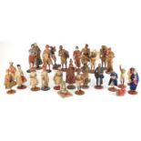 Collection of mostly hand painted pottery figures, some raised on wooden plinth bases, the largest