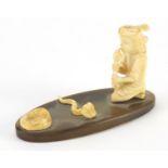 Indian ivory carving of a snake charmer on oval horn base, 6cm High x 10cm in length :For Further