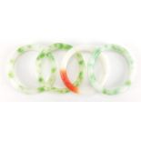 Four Chinese white, green and red jade bangles, the largest approximately 8cm in diameter,
