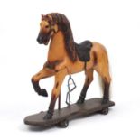 19th century French carved wood and painted pull along horse with metal wheels, 78cm high : For