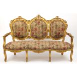 Ornate French gilt wood three seater settee with floral upholstery, carved with rosettes and