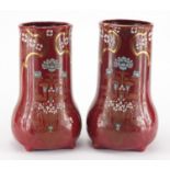 Pair of Art Nouveau pottery four footed vases, each enamelled and gilded with stylised flowers,