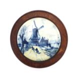 Dutch delft charger hand painted with figures before a windmill beside a canal, housed in an oak
