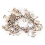 Heavy silver charm bracelet with a large selection of mostly silver charms including articulate