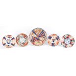 Four Japanese Imari shallow dishes and a charger hand painted with panels of flowers, the largest