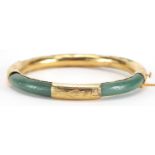 Chinese green jade bangle with gold coloured metal mounts, 7.8cm in diameter, approximate weight