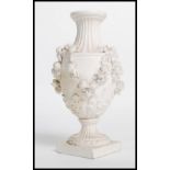 A 19th century Derby parian bisque ware vase raised on a square base with relief decoration of