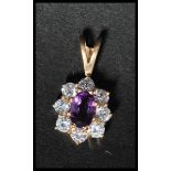 A hallmarked 9ct gold cluster pendant set with a central oval cut amethyst surrounded by  halo of