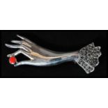 A sterling silver and marcasite brooch in the form of a ladies hand holding a piece of coral. Weighs