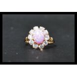 A 14ct gold cluster ring set wit a central pink opal style stone surrounded by a halo of white