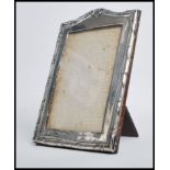 A hallmarked silver Art Nouveau easel back picture frame having a scrolled top with leaves to