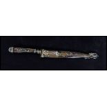 A white metal decorative American wild west paper knife and scabbard. Depicting cowboy and bull with