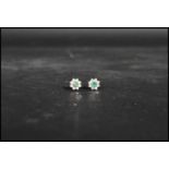 A pair of 9ct gold green and white stone cluster earrings. The central green stones having a halo of
