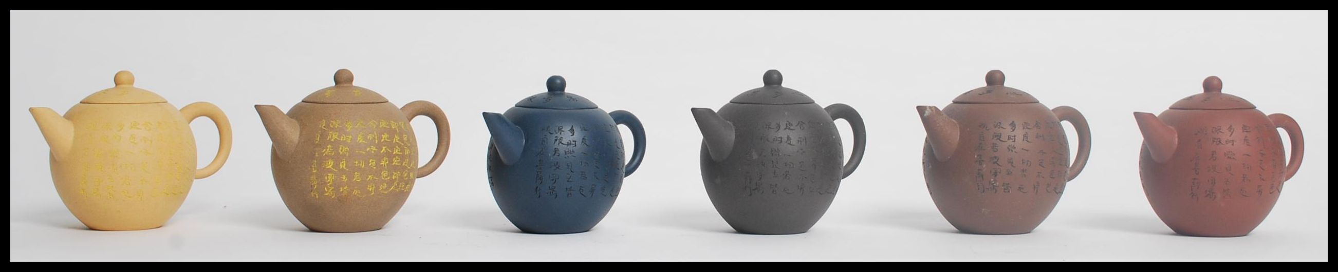 A group of six Chinese Yi Zing terracotta teapots of bulbous form having calligraphy decoration.