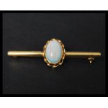 A hallmarked 9ct gold and opal brooch pin set with a single opal cabochon in a twist setting