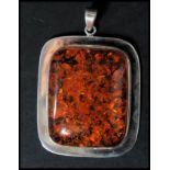 A large sterling silver and amber necklace pendant of rectangular form having a large central