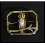 A 10ct gold brooch having an enamel owl with natur