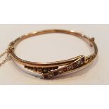 A Victorian 9ct gold, ruby and pearl channel set ladies bangle bracelet complete with the safety