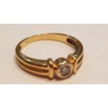 An 18ct yellow gold diamond single stone ladies ring with central round cut stone in buckle setting.