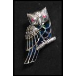 A sterling silver plique a jour brooch in the form of an owl rasting on a branch with ruby set eyes.