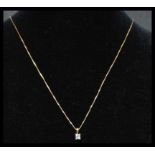 An 18ct gold and diamond drop pendant necklace strung with an square cut diamond on a box link