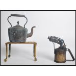 A pierced brass trivet stand raised on claw feet along with a British made blowtorch and a kettle.