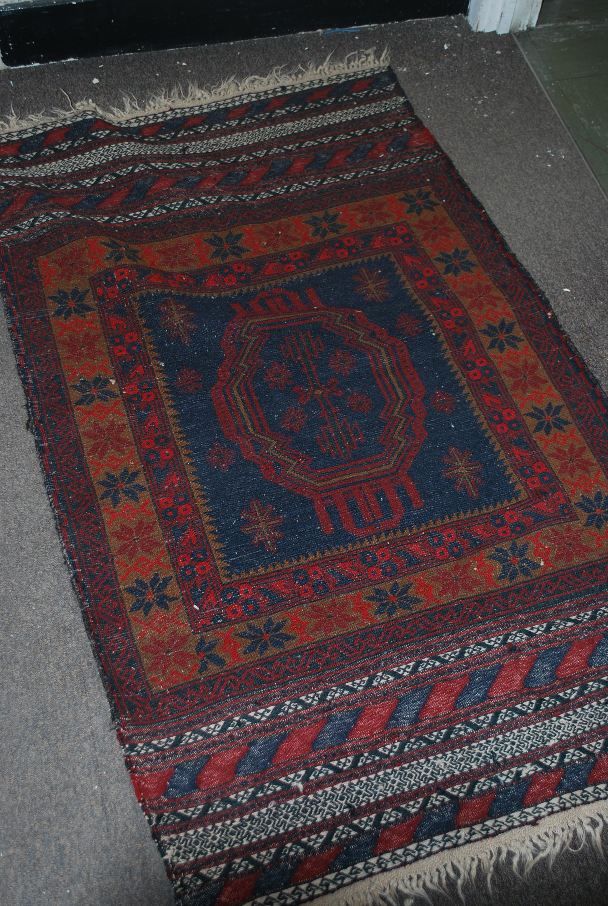 A Persian Islamic floor rug having a deep red and